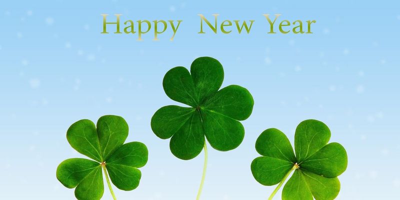 Drei schöne grüne Kleeblätter vor einem hellblauen Hintergrund mit dem Text "Happy new Year" 